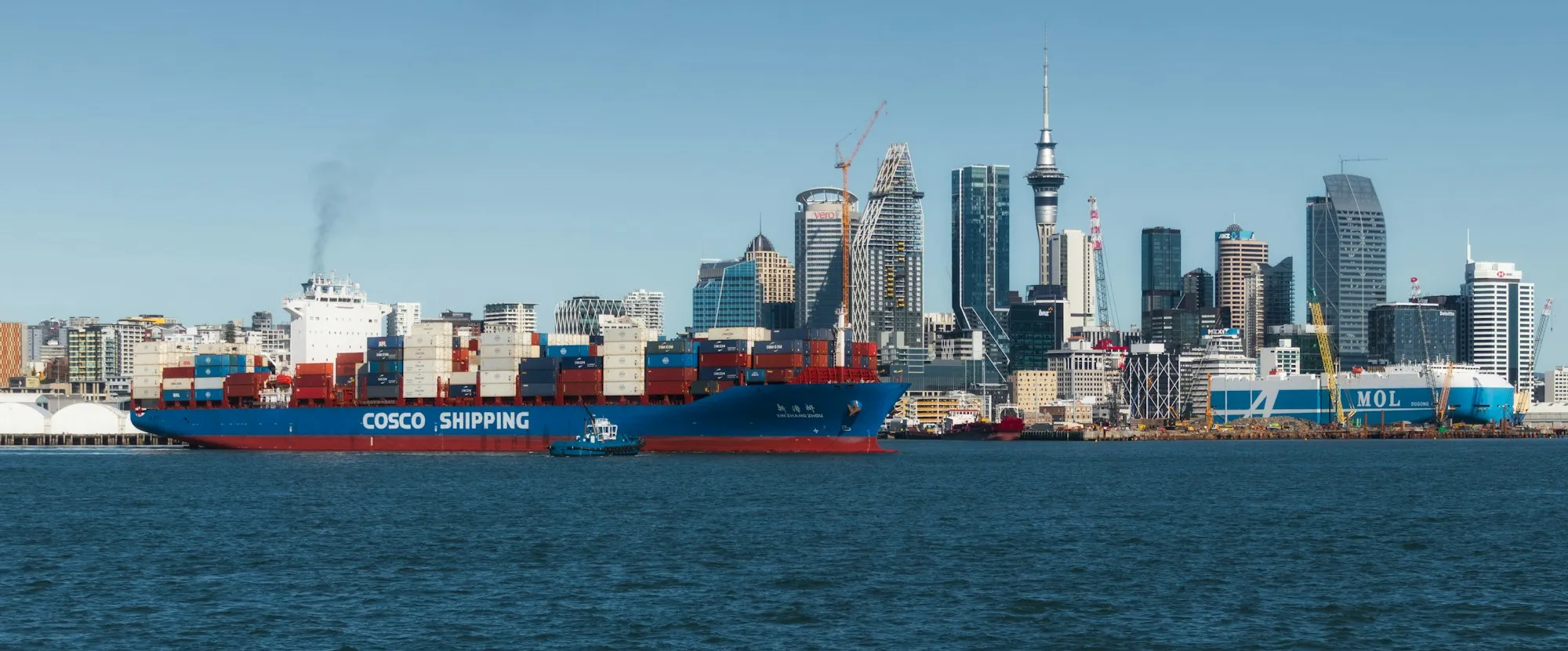 A container ship in Auckland harbour with the Sky Tower and city skyline behind