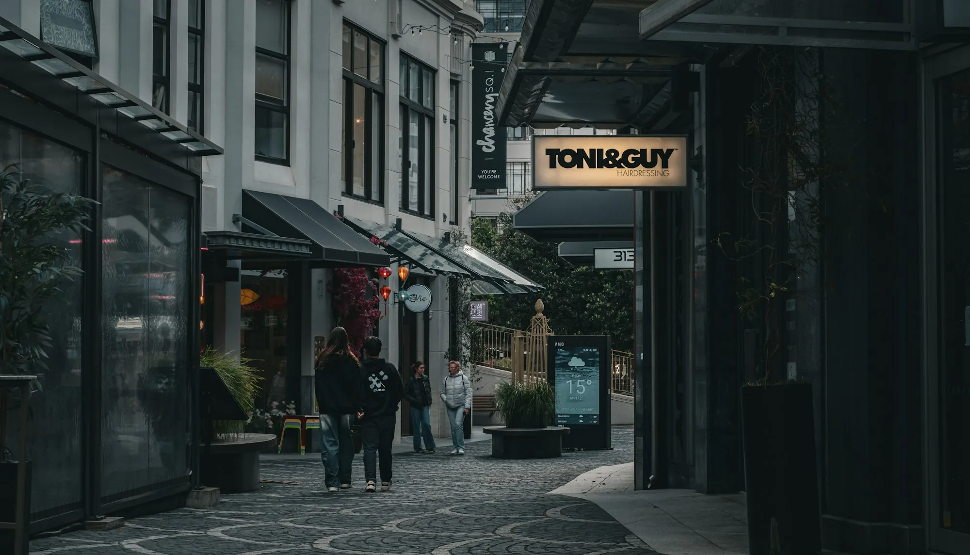 People walking along a cobbled laneway lined with small shops in central Auckland