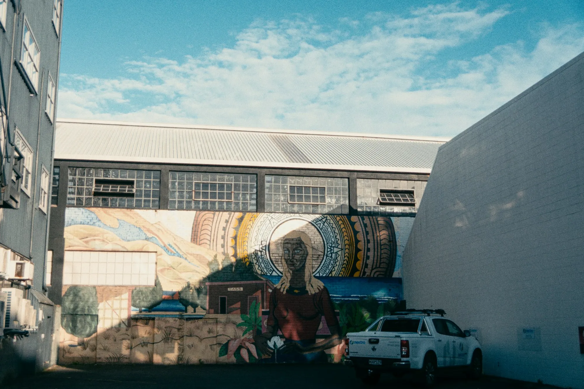 A work ute parked beside a warehouse wall with a mural in Auckland