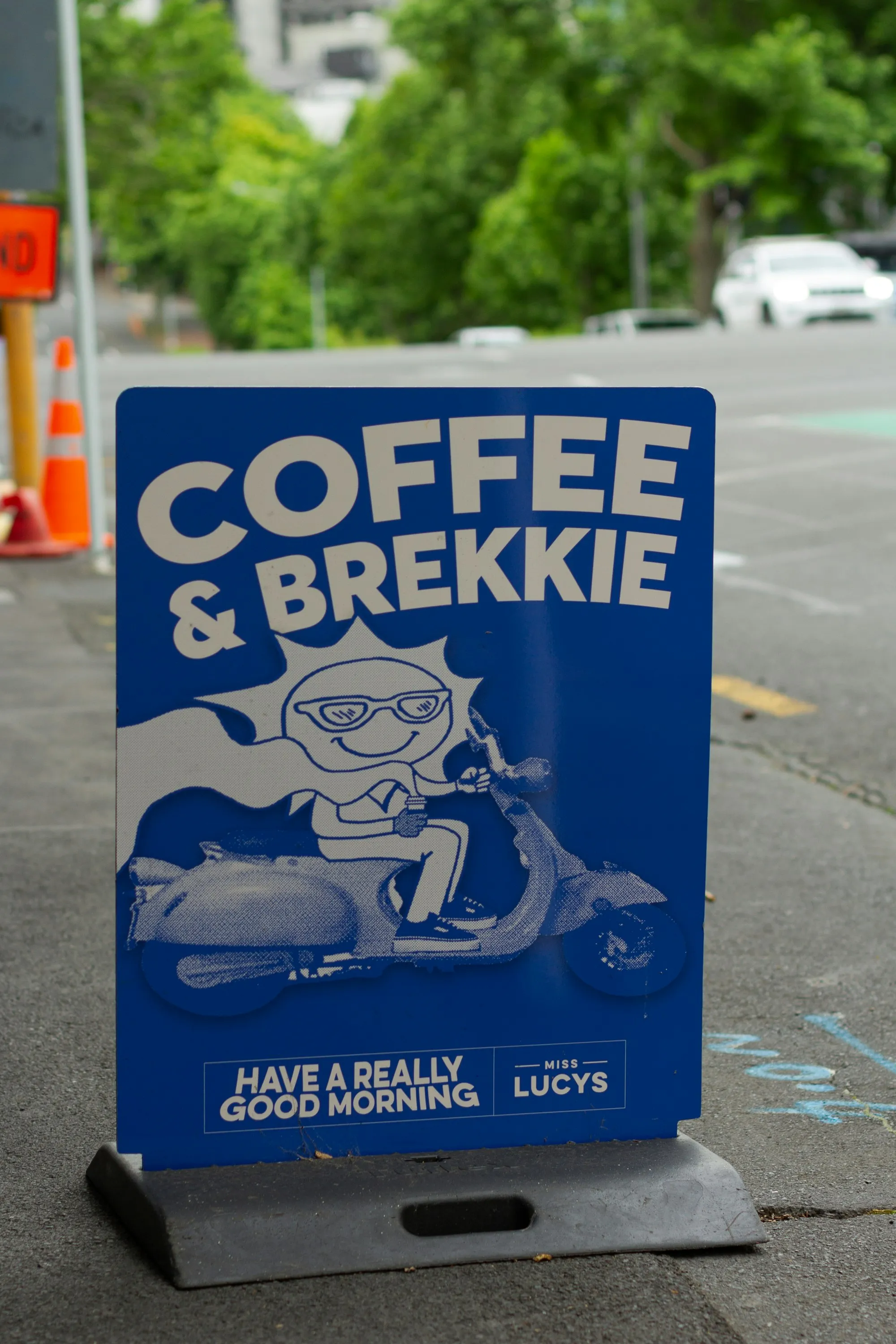 A blue 'Coffee & Brekkie' street sign outside an Auckland café