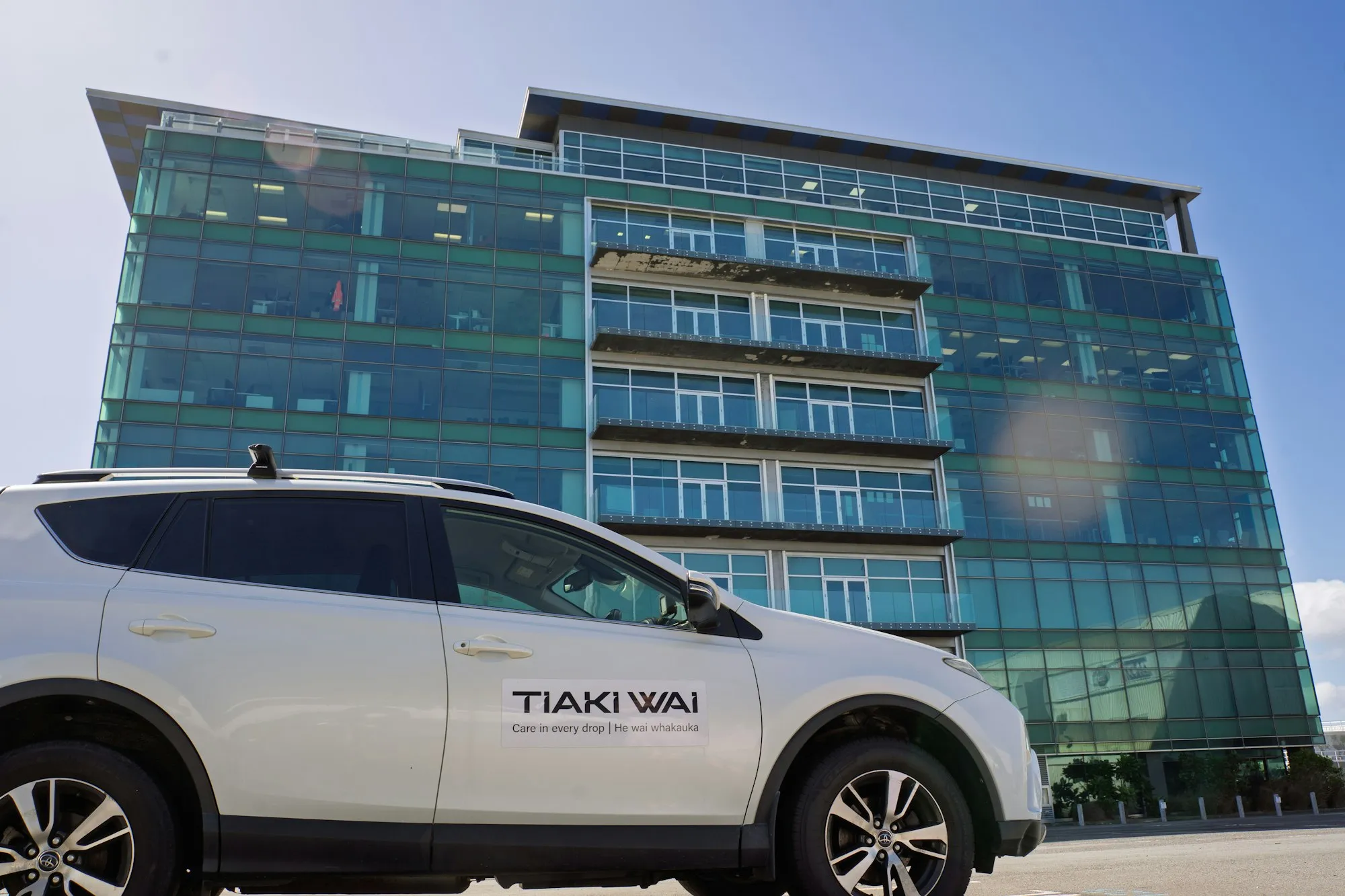 A company vehicle parked in front of a glass office building in Wellington